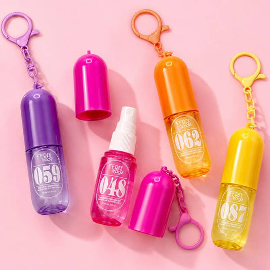 Six small translucent personal spray bottles with keychain clips in purple, pink, orange, and yellow, arranged on a light pink background. The bottles have white printed numbers on the front.